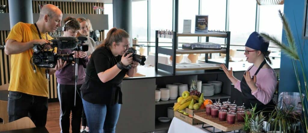 Emily står i frokostbar for å servere smoothie til kamera-crew