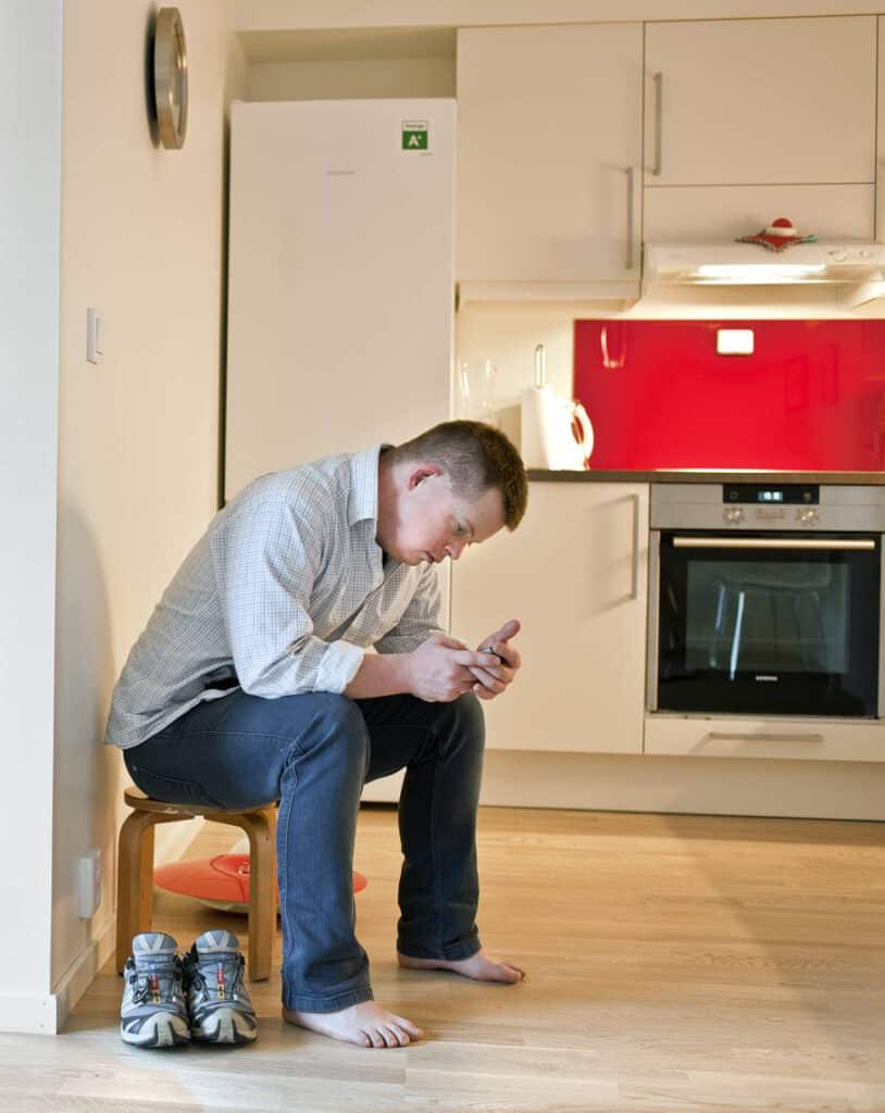 bilde av mann med Downs syndrom som er på telefon ved kjøkkenet