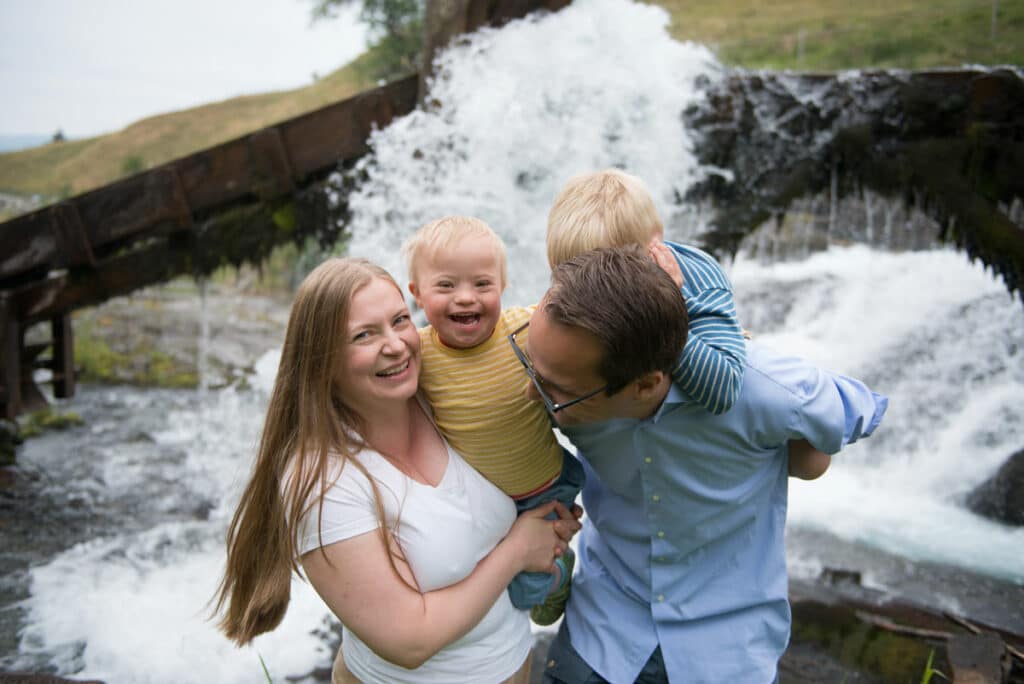 Bilde av styreleder i NNDS Randi Ødegaard sin familie, foran en foss. Hennes ene sønn har Downs syndrom.