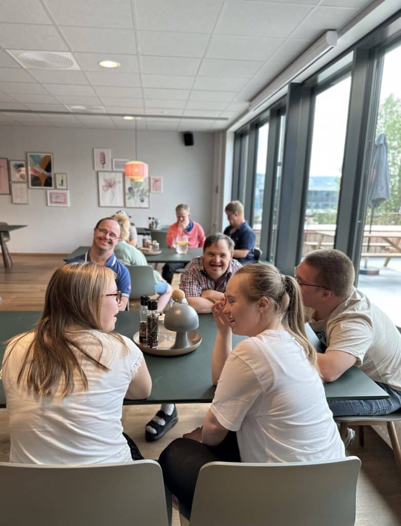 Menensker som sitter rundt et bord og snakker sammen