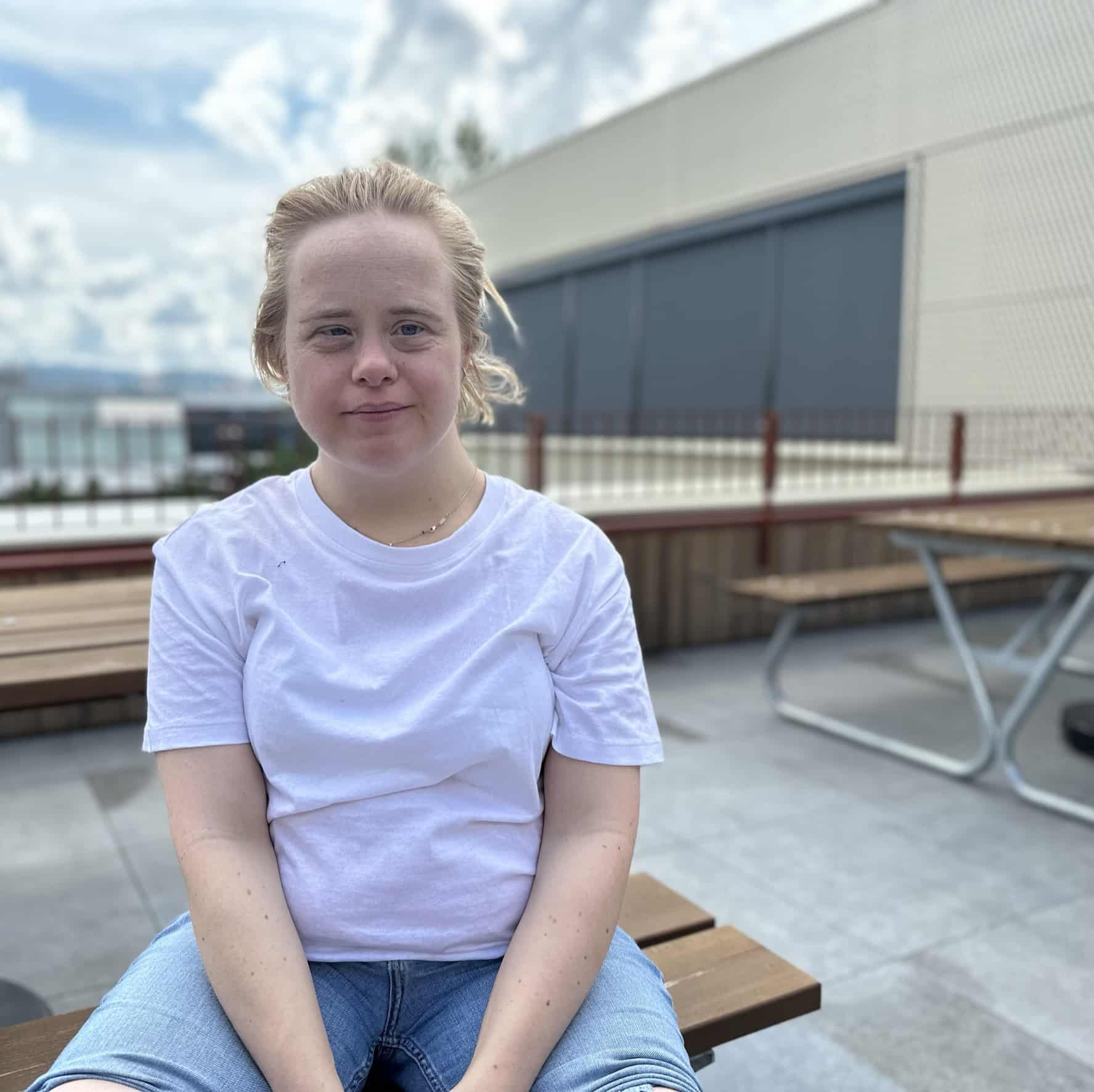 Kvinne med Downs syndrom sitter på et bord ute