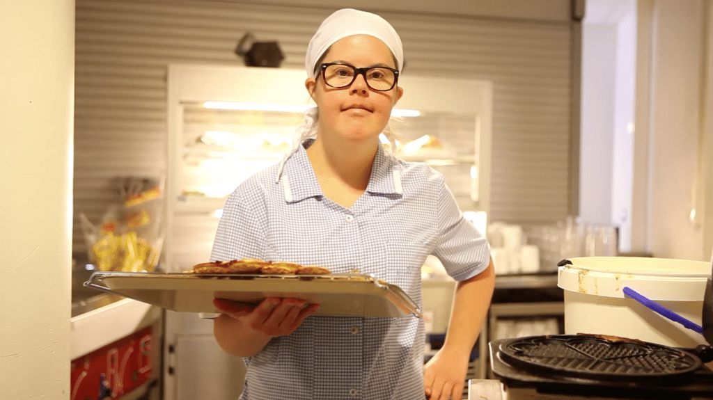 Kvinne med Downs syndrom i et kjøkken som holder et brett med vafler