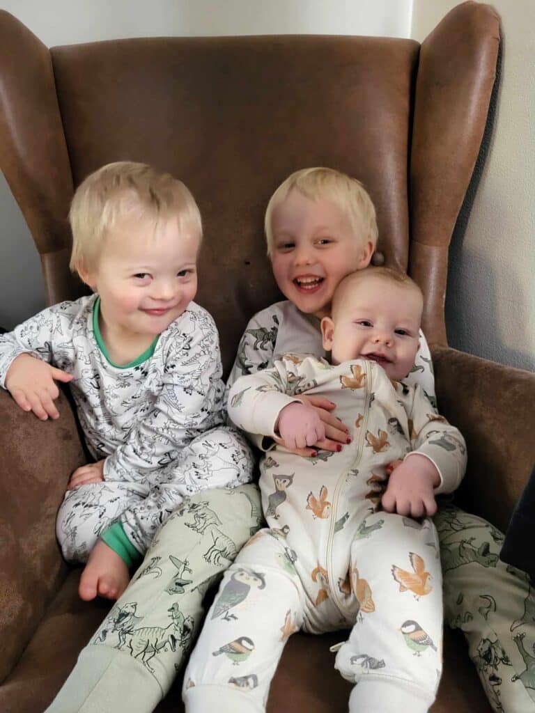 Tre små barn som sitter sammen i en lenestol