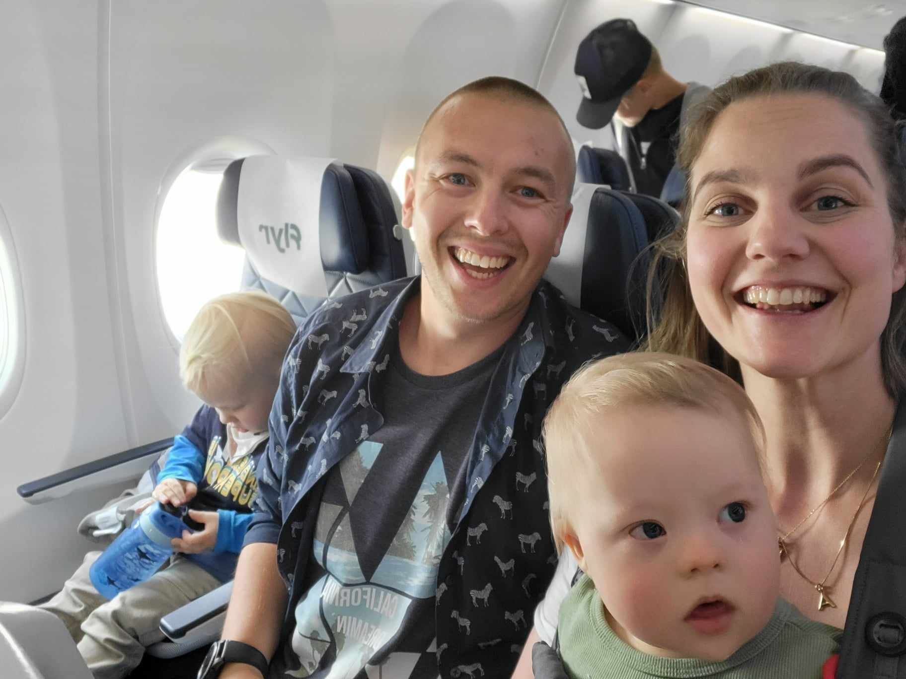 Familie med to barn og to voksne som sitter inne i et fly