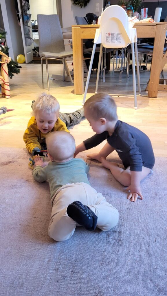 Tre små barn som leker på gulvet