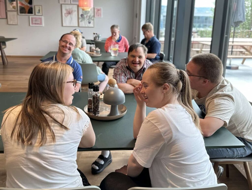 En gruppe mennesker med Downs syndrom som sitter rundt et bord og snakker sammen
