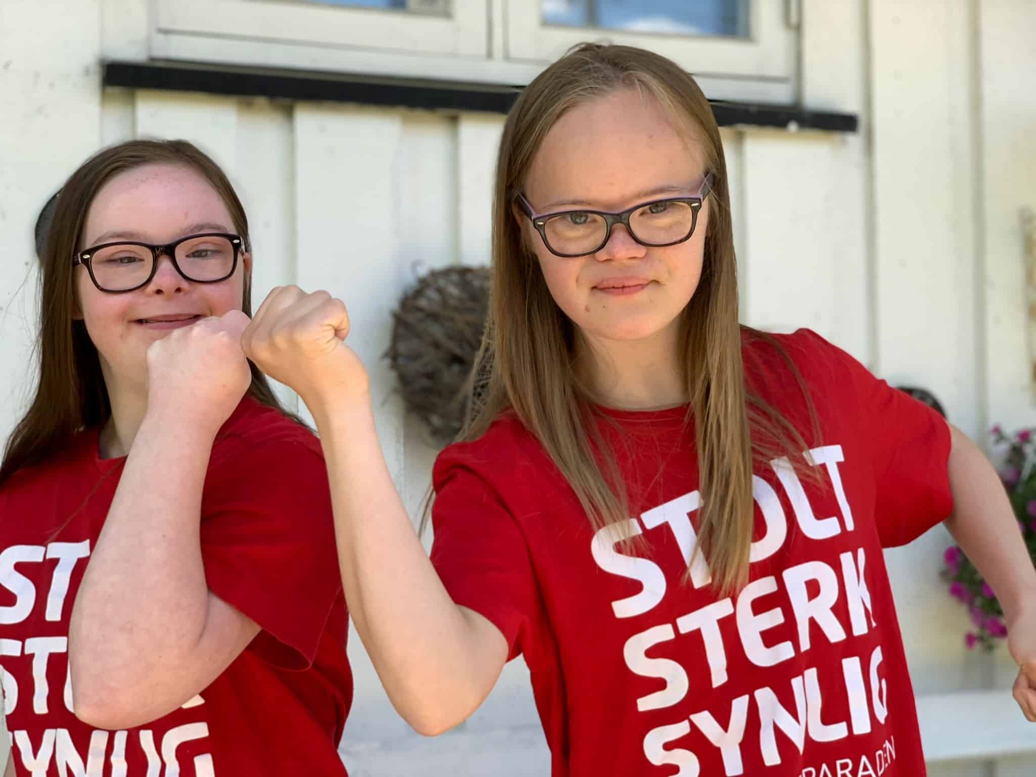 To jenter med Downs syndrom som står sammen og viser muskler