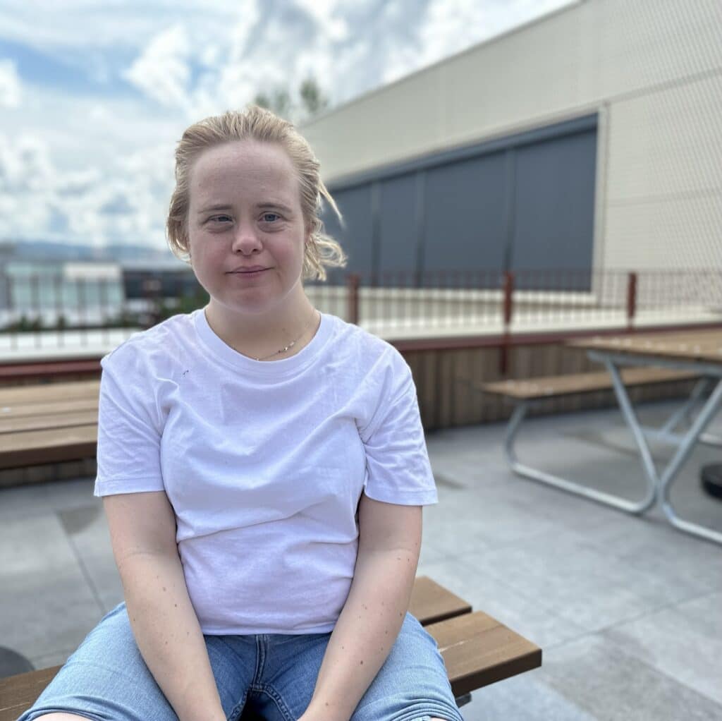 Kvinne med Downs syndrom sitter vet et bord utendørs