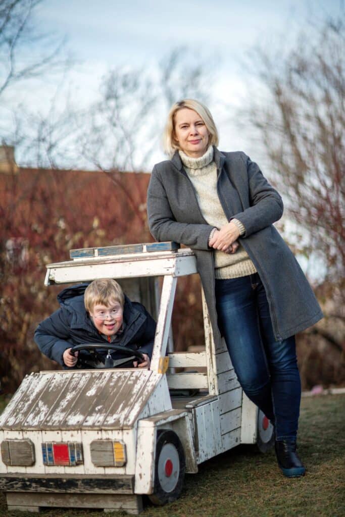 Mor og sønn. Sønnen sitter i en lekebil.