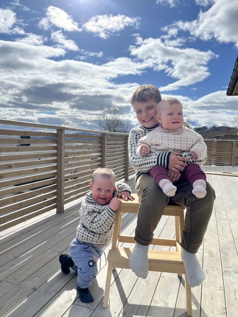 Edvard med Downs syndrom sammen med storebror og lillesøster på verandaen