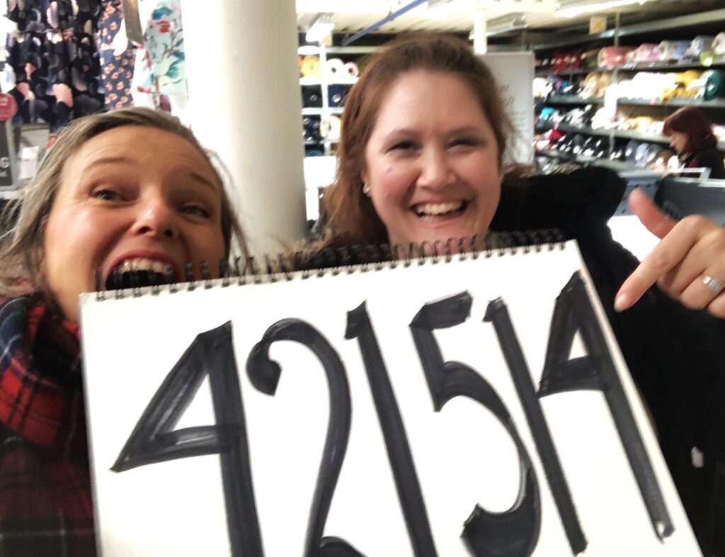To glade damer peker på en plakat med tallet 421514