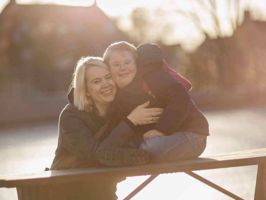 mor og sønn som sitter sammen på parkbenk og klemmer