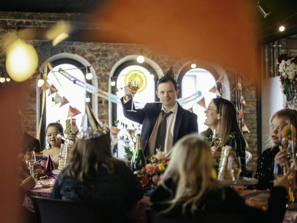 Mann med Downs syndrom som skåler og feirer Verdensdagen for Downs syndrom 21. mars