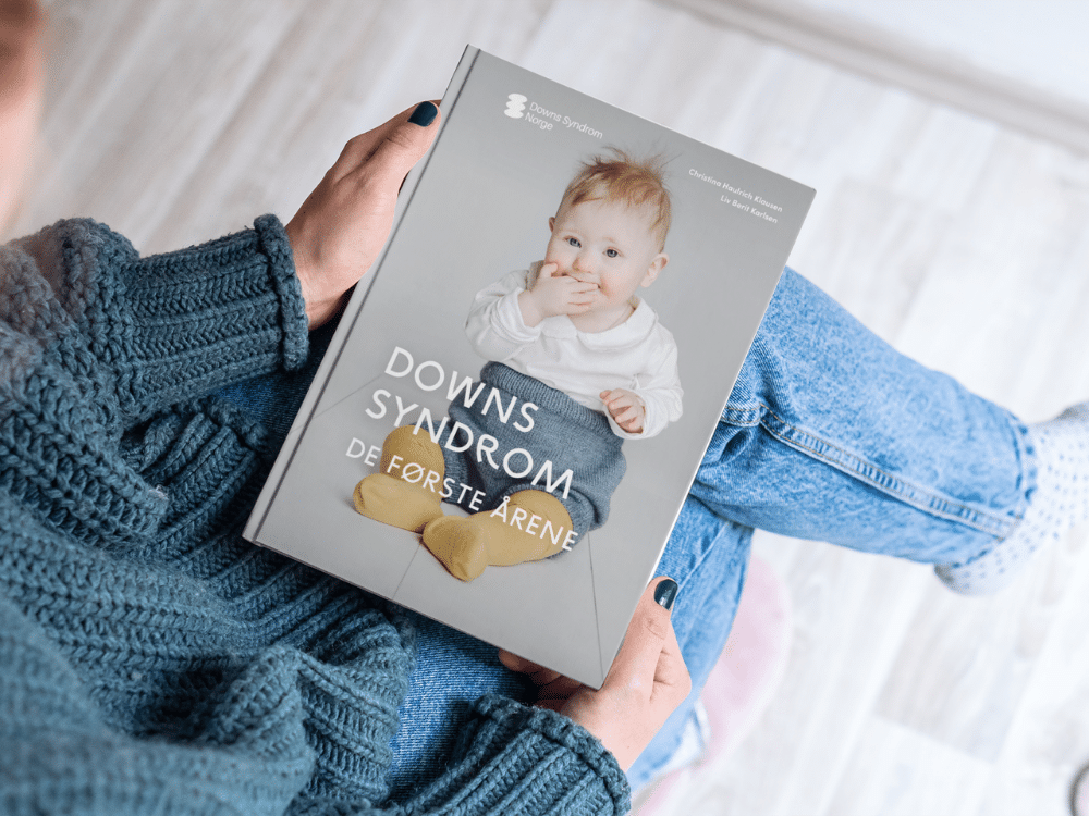 Boken "Downs syndrom - de første årene" som holdes av en kvinne